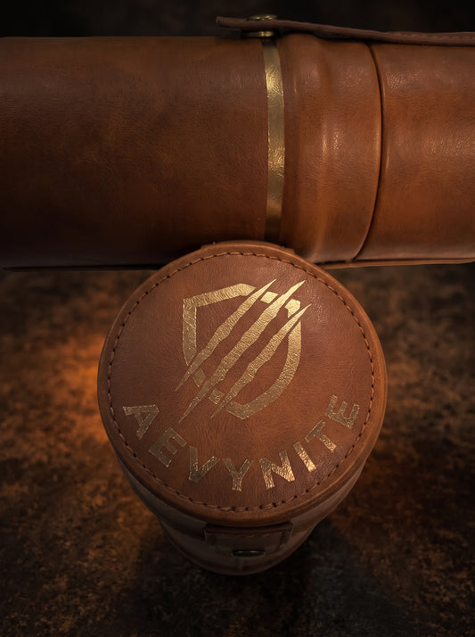 Brown leather playmat case with gold emblem and 'AEVYNITE' branding on a textured surface
